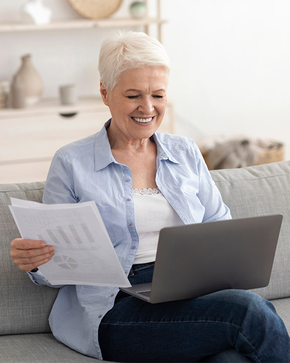 senior woman on the computer with financial paperwork in her hand safest place for retirement money