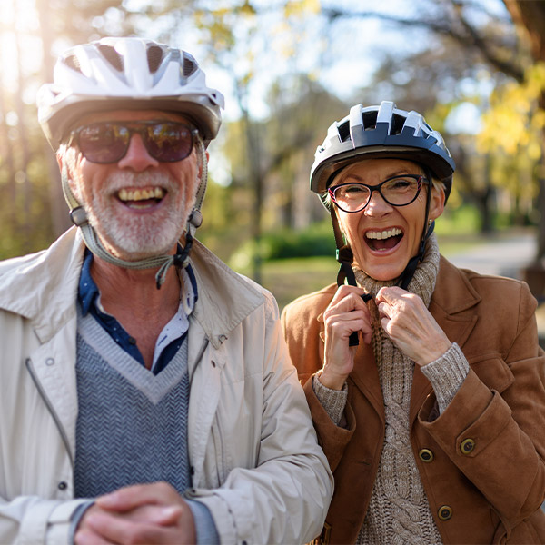 smiling senior couple putting helmets on to go for a bike ride keys to a successful retirement